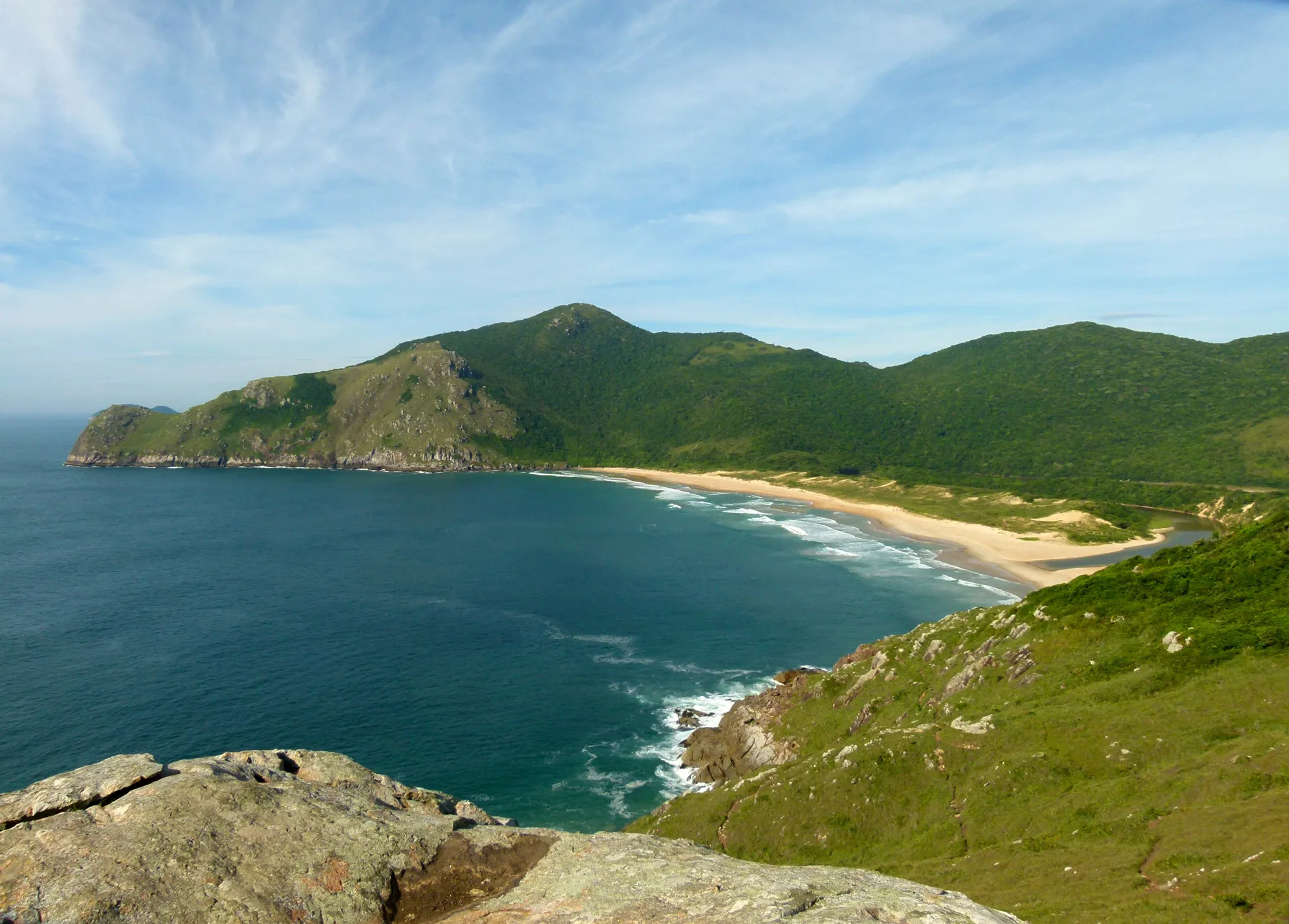 Praia da Lagoinha do Leste vista do alto, com mar verde-azulado, faixa de areia e morros cobertos de mata