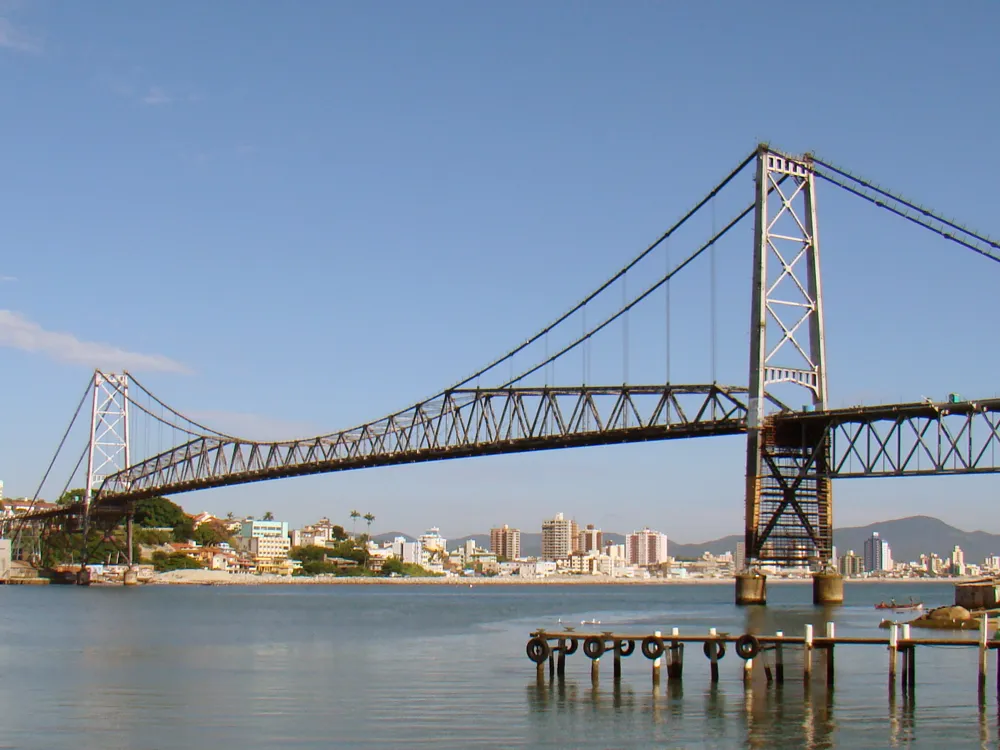 Ponte Hercílio Luz durante o dia, estrutura pênsil sobre a baía com céu azul