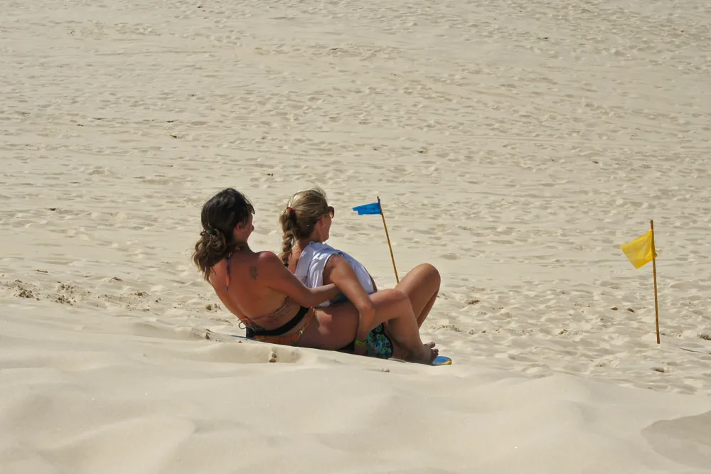 Pessoa descendo as dunas da Joaquina em uma prancha de sandboard
